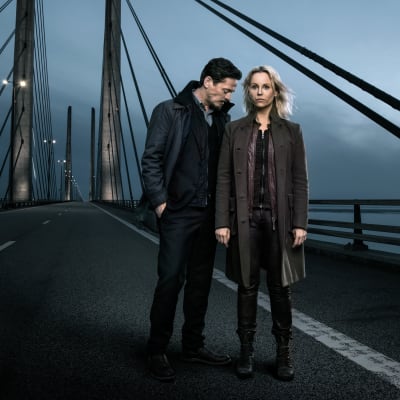 Karaktärerna Henrik och Saga står på en bro i mörkret.