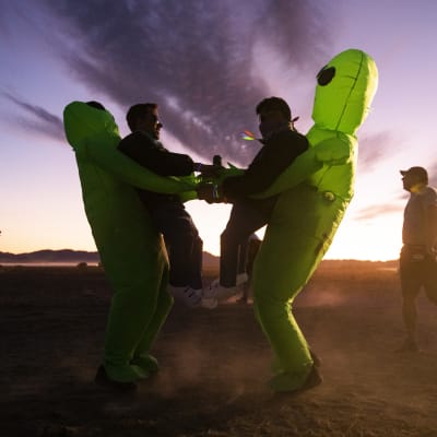 Två personer utklädda till rymdvarelser dansar i soluppgången i byn Rachel utanför Area 51.