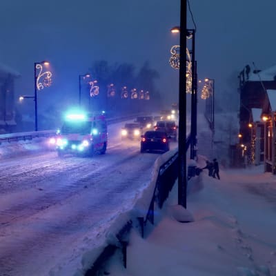 En ambulans kör över Mannerheimgatans bro i Borgå. Det är mörkt och mycket snö på marken.