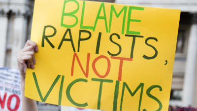 Kvinna som håller upp skylt där det står: Skyll på våldtäktsmännen, inte på offren.