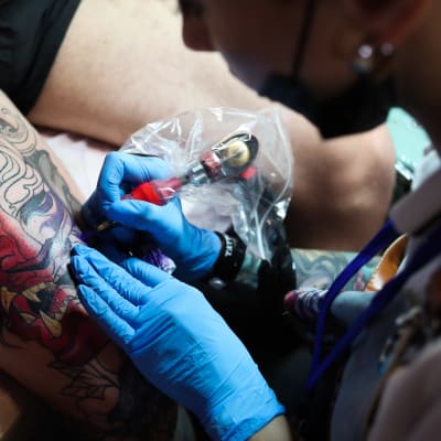 Tatuoija työskentelee värikkään tatuoinnin parissa
