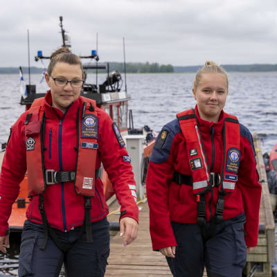 Två personer på en brygga med två båtar i bakgrunden.