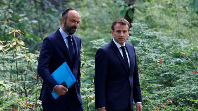 Edouard Philippe och Emmanuel Macron går sida vid sida ute i en trädgård. 29.6.2020
