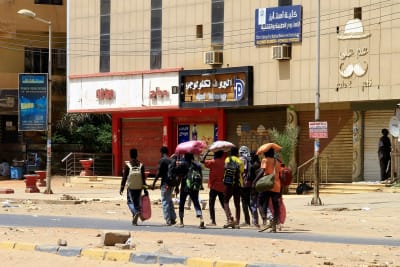 Ihmiset, jotka kantavat omaisuuttaan, kävelevät kadulla Khartumissa 16. huhtikuuta.