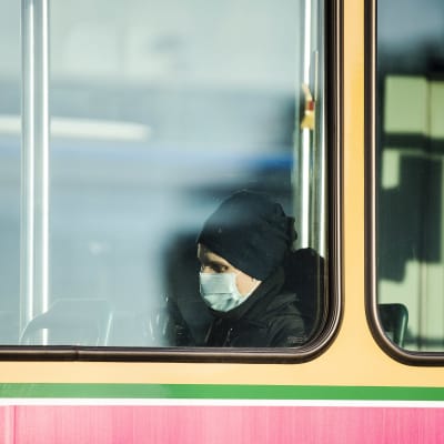 Man med munskydd i spårvagn i Helsingfors. 