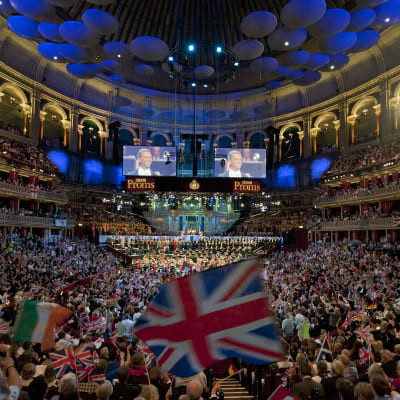 Valtava yleisöjoukko Royal Albert Hallin salissa. Etualalla suuri Britannian lippu.