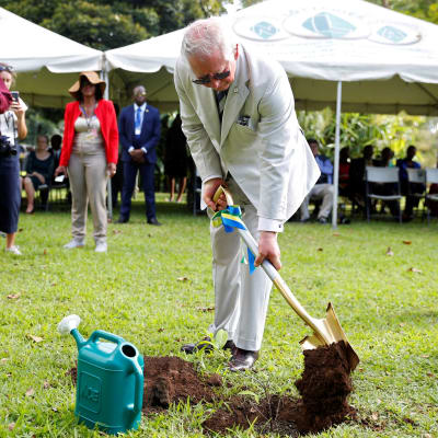 Prins Charles gräver i marken med en spade.
