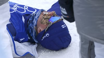 Remi Lindholm ligger på snön efter målgången på tremilen.