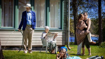 En familj i flera generationer på en gräsmatta framför en sommarvilla.