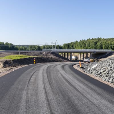 En nybyggd väg med ny asfalt. Vägen går under en bro. Det är sommar och sol. Karis, Läpp, riksväg 25.