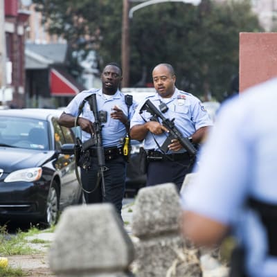 Två poliser med automatgevär går på gatan.