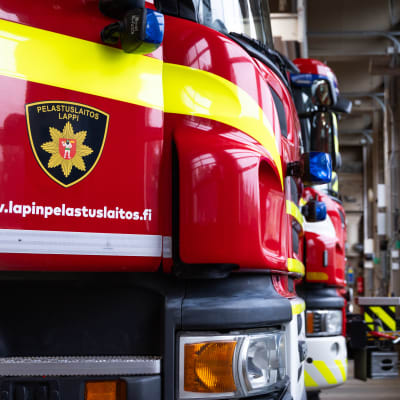 Lapin pelastuslaitoksen paloautojen keulat tallissa.