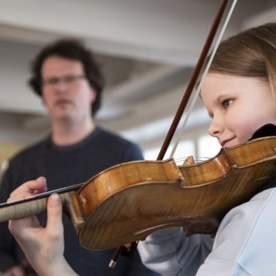Violinisten Lilja Haatainen övar. I bakgrunden syns hennes lärare, Janne Malmivaara.
