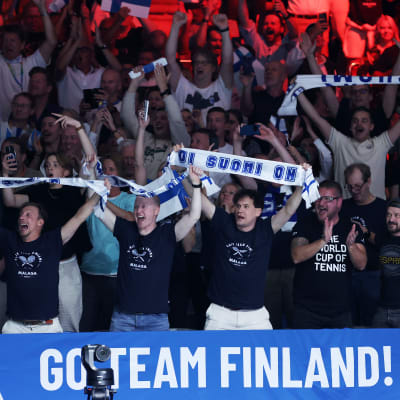 Suomalaiskannattajat iloitsevat Malagan tennisstadionin katsomossa.