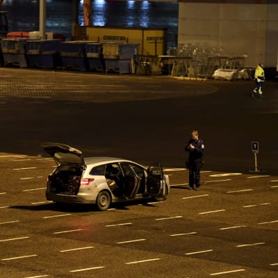 Polisbilar parkerade vid Olympiaterminalen i Helsingfors. En polis står bredvid en bil med öppna dörrar och öppen baggagelucka.