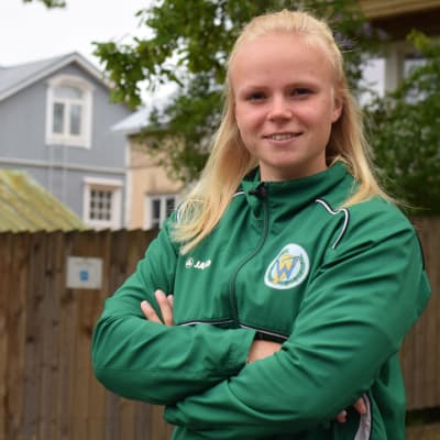 En ung kvinna med grön klubbjacka med ett "w" på bröstfickan. Bokstaven symboliserar Wågen, en kanotklubb i Ekenäs.