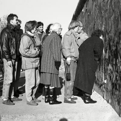 Människor tittar igenom ett hål i Berlinmuren 11.11.1989.