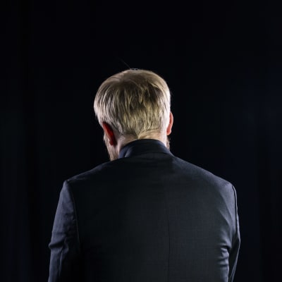 Pekka Vahvanen takaa päin kuvattuna mustassa studiossa.