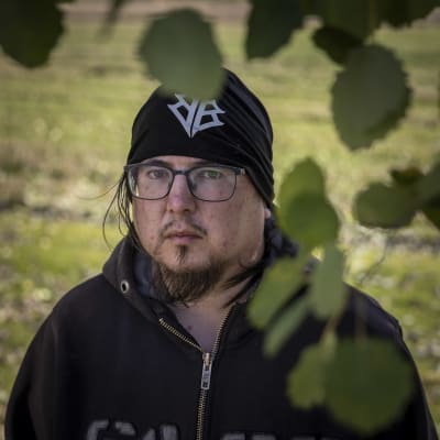 Mies puun lehtien ympäröimänä. 
