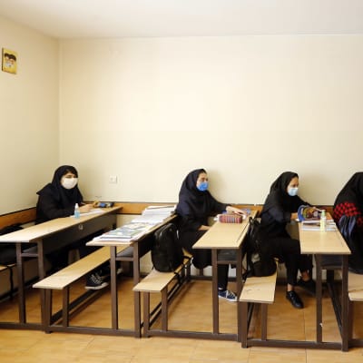 Iranilaiset lukiotytöt, joilla on kasvomaski, osallistuvat tunnille.