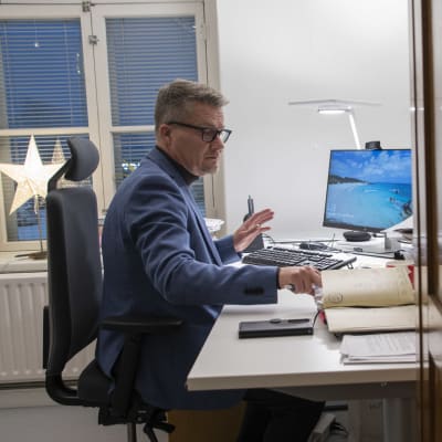 En man sitter och jobbar vid sitt skrivbord och kollar i sin kalender.