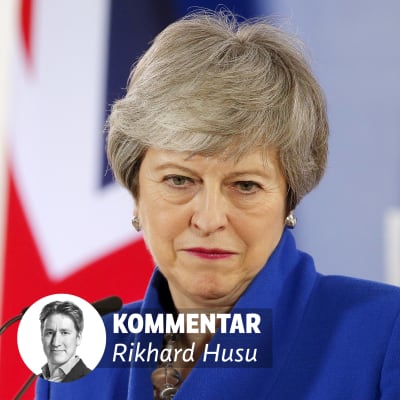 Theresa May ser besviken ut med en vägg med texten EU på bakom sig.