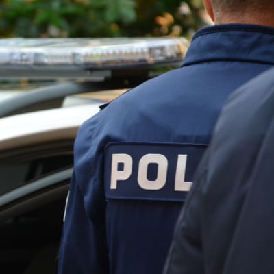 Polis framför polisbil.
