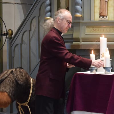Kirkkoherra Kari Penttinen sytyttää kynttilöitä Noormarkun kirkossa.