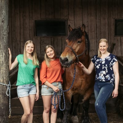 Kolme eläinlääketieteen kandia poseeraa kameralle hevosen kanssa