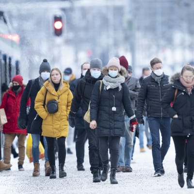 Människor i munskydd stiger ut ur ett tåg i Helsingfors.