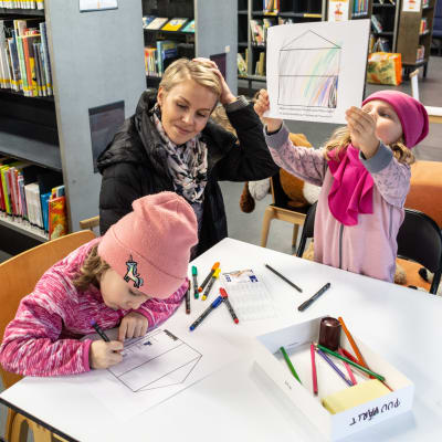Barn och mamma som sitter och ritar i ett bibliotek.