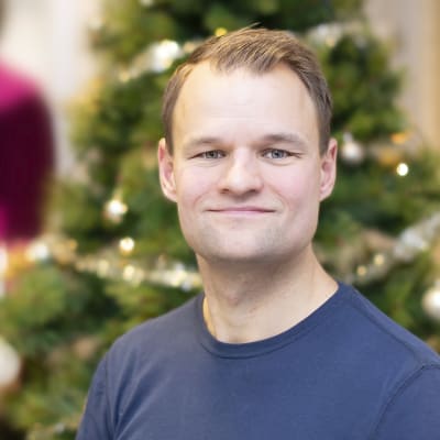 Peter Siegfrids i blå tröja framför en julgran.