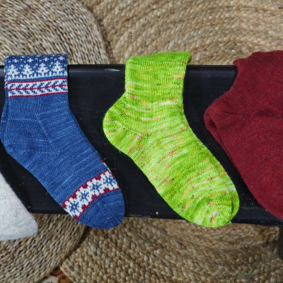 Neljä käsinkudottuja sukkia eri väreissä.