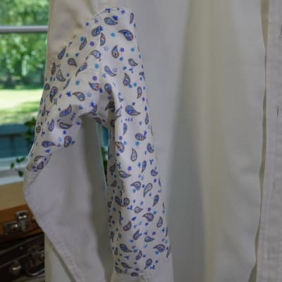 En vit skjorta som lappats med ett paisleymönstrat tyg under ärmen.