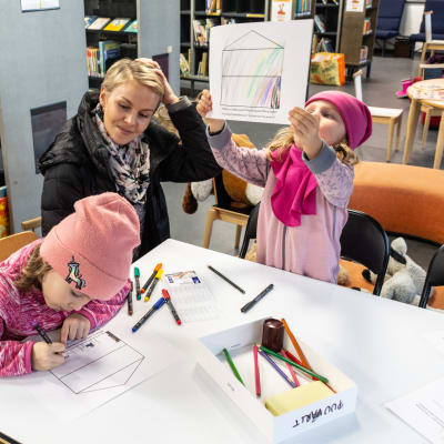 Barn och mamma som sitter och ritar i ett bibliotek.