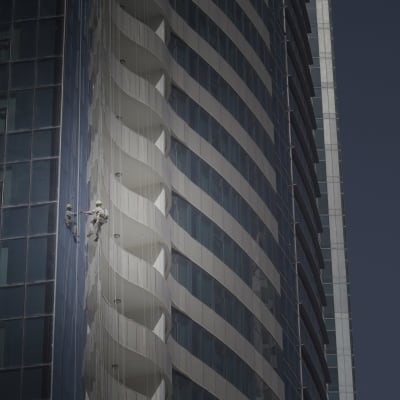 En migrantarbetare jobbar på ett högt torn.