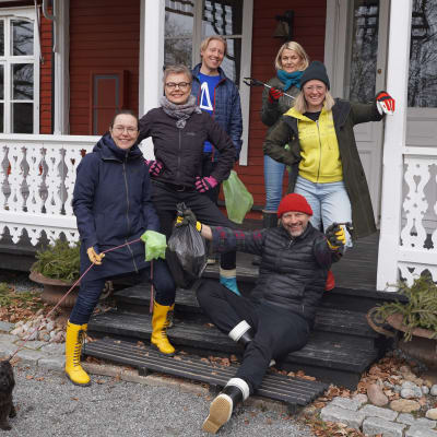Sex personer står på en veranda.
