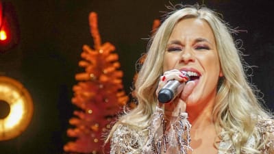 Krista Siegfrids med rött scenljus i bakgrunden.