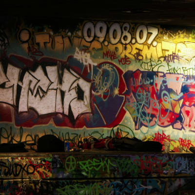 Två personer i står vid en graffitimålad vägg.