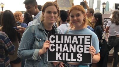 Sophia Murphy och Julianna Marton med New York i bakgrunden. De håller ett plakat med texten "Climate change kills".