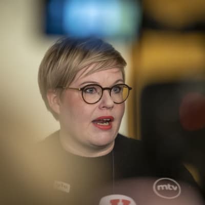 Närbild av finansminister Annika Saarikko med runda glasögonbågar och svart skjorta.  