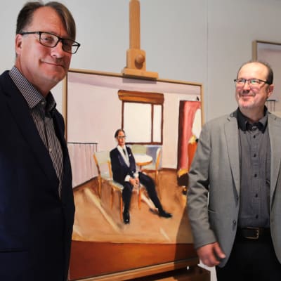 Taiteenkerääjä Kari Niemistö ja kuvataiteilija Viggo Wallensköld taustallaan kaksi Wallensköldin Niemistöstä maalaamaa taulua.