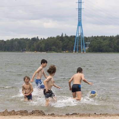 Neljä lasta leikkii pallolla vedessä. 