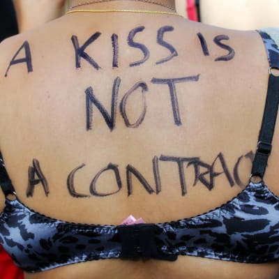 En kvinna demonstrerar mot våldtäkt med texten "en kyss är inget kontrakt".
