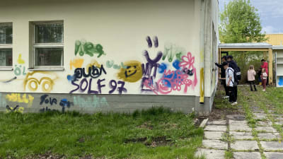 Barn och unga täcker in gammal skolbyggnad med grafitti.