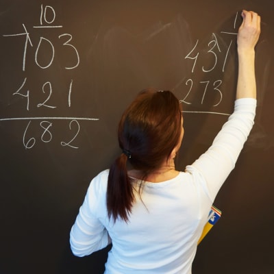  En grundskolelärare skriver på en svart tavla