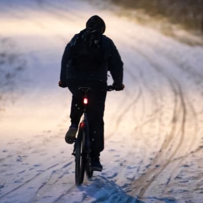 Pyöräilijä lumisella tiellä.