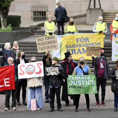Människor demonstrerar utanför Ständerhuset 8.9.2021. De håller upp plakat med texter för klimatet.