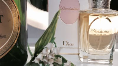 En flaska champagne, en parfymflaska av Dior och liljekonvaljer i plast.