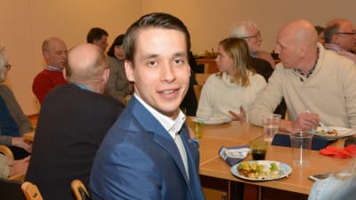 Henrik Wickström sitter vid ett bord tillsammans med en drös andra.